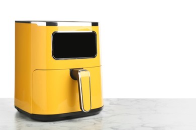 Photo of Modern yellow air fryer on marble table against white background