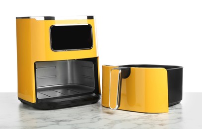 Photo of Modern yellow air fryer on marble table against white background