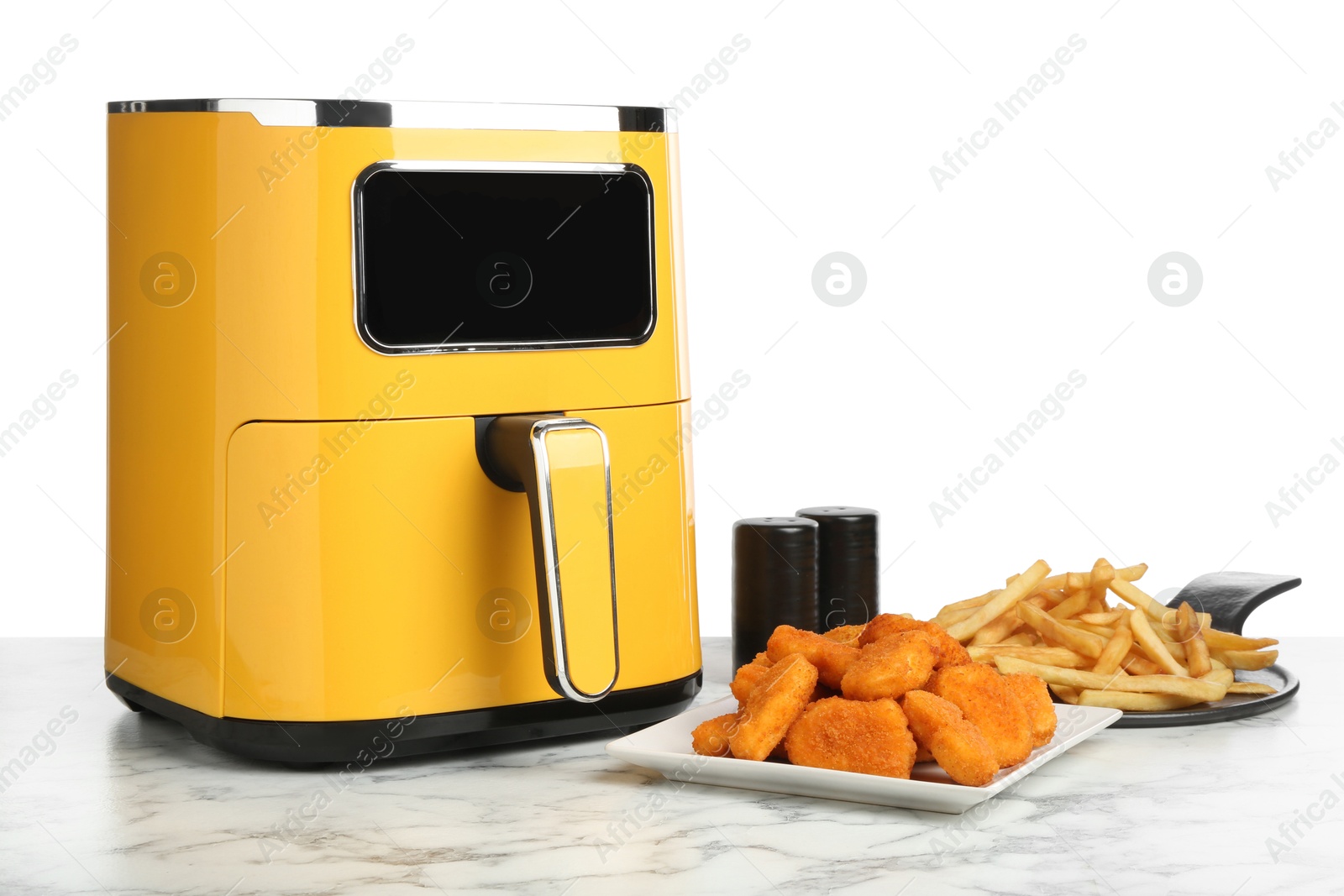 Photo of Modern air fryer and cooked meals on marble table against white background