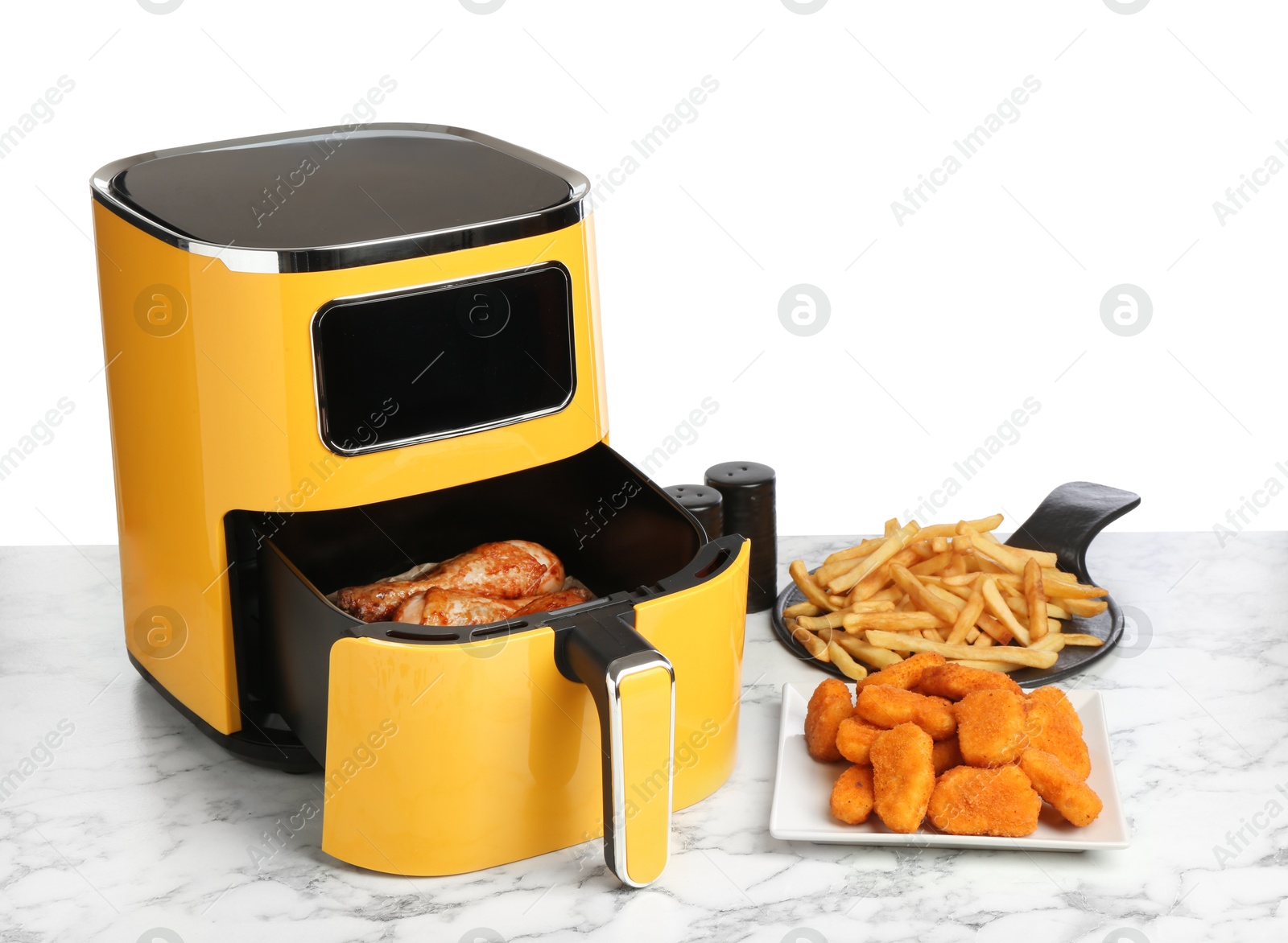 Photo of Modern air fryer and cooked meals on marble table against white background