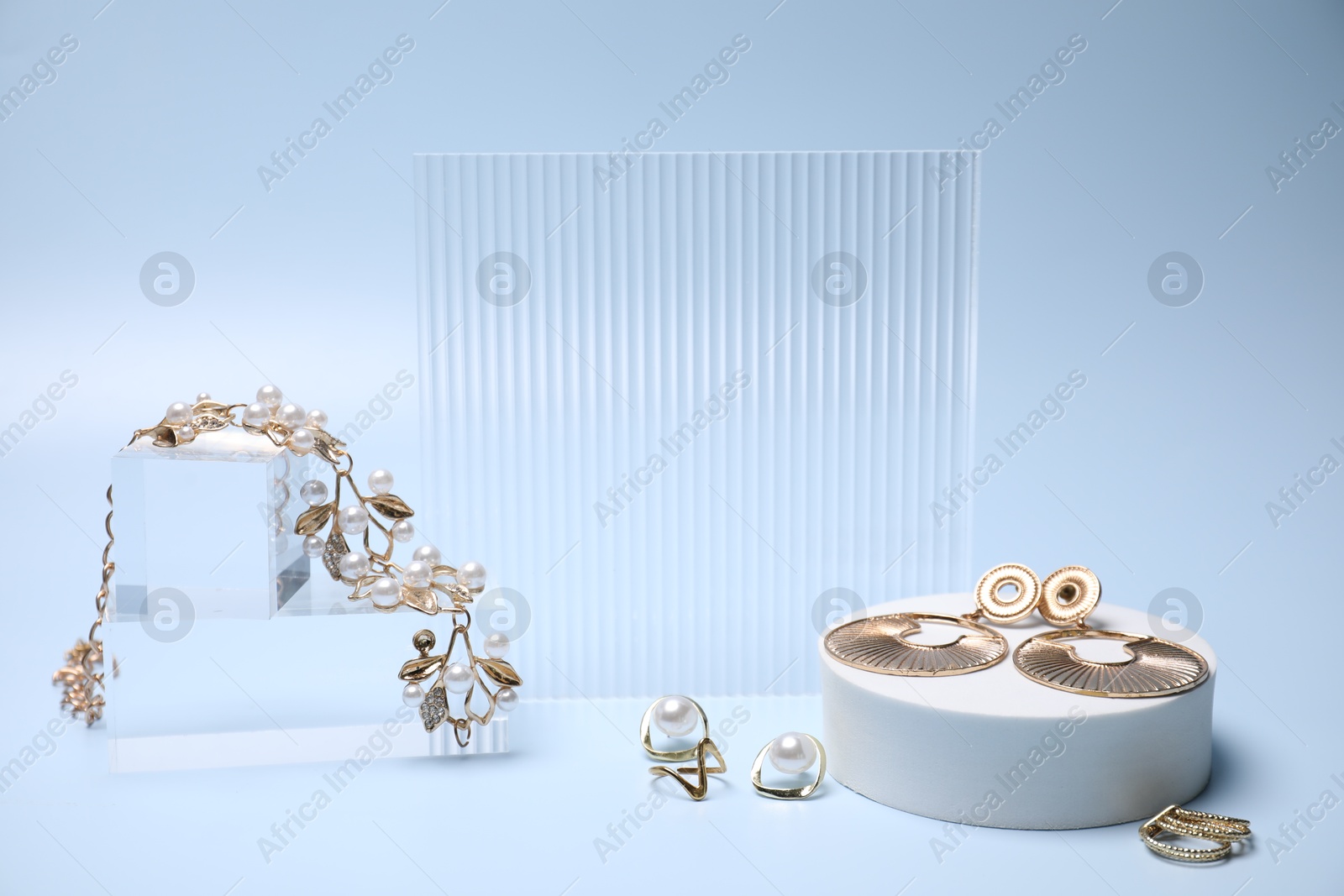 Photo of Stylish presentation of gold jewelry on light blue background