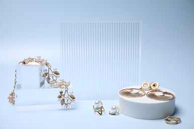 Photo of Stylish presentation of gold jewelry on light blue background