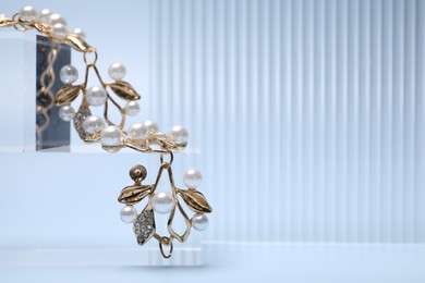 Photo of Stylish presentation of gold bracelet on light blue background, closeup. Space for text