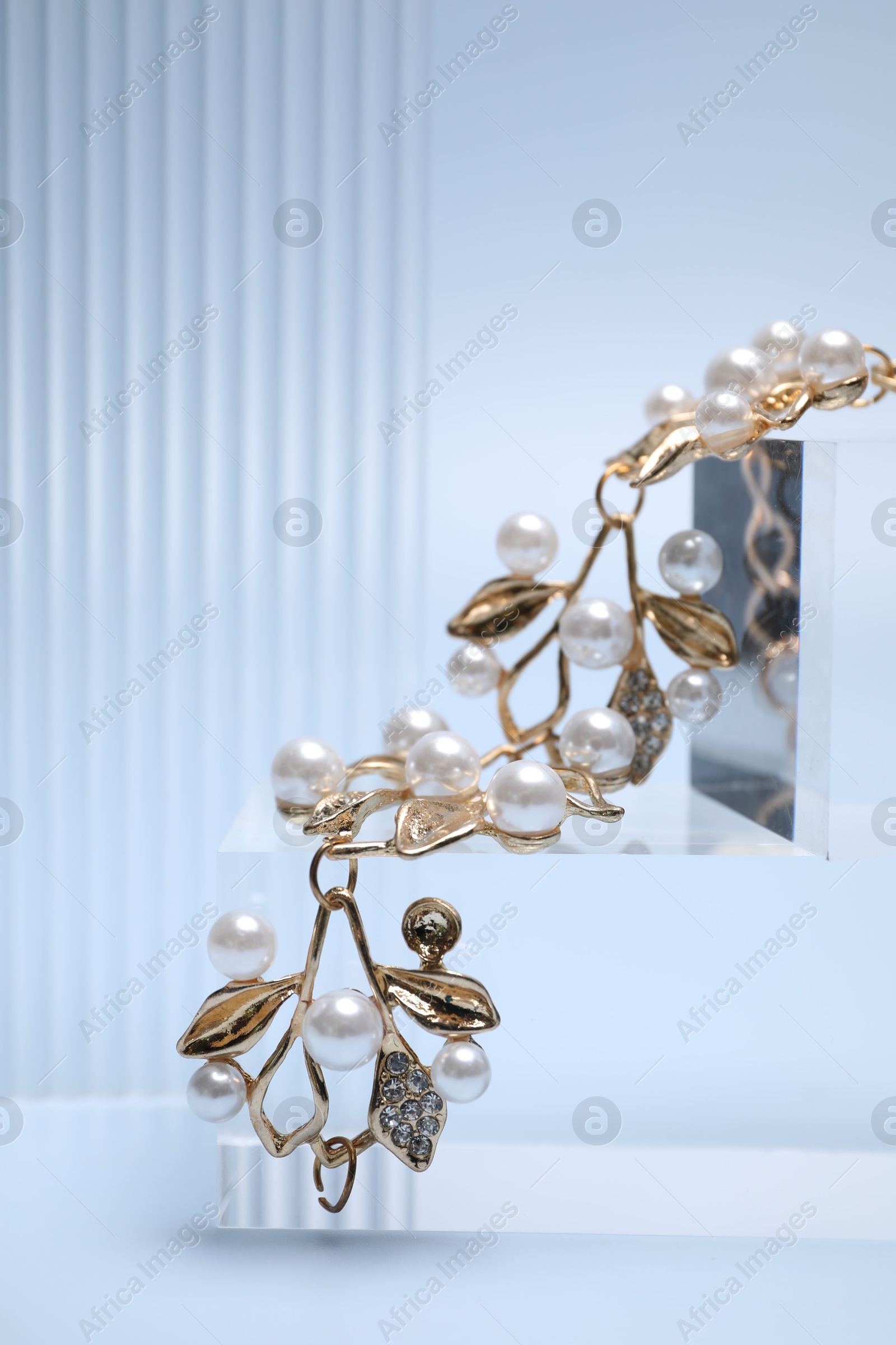 Photo of Stylish presentation of gold bracelet on light blue background, closeup. Space for text