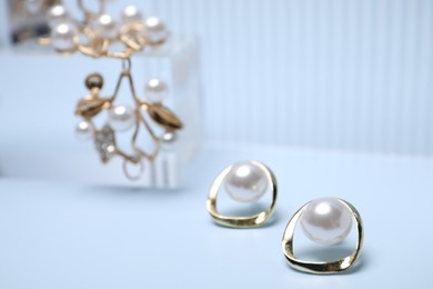 Photo of Stylish gold earrings on light blue background, closeup. Space for text