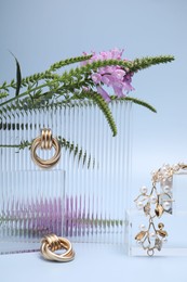 Photo of Stylish presentation of gold jewelry on light blue background
