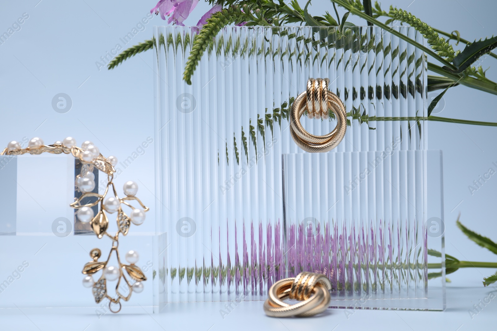 Photo of Stylish presentation of gold jewelry on light blue background