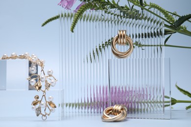 Photo of Stylish presentation of gold jewelry on light blue background