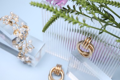 Photo of Stylish presentation of gold jewelry on light blue background, closeup