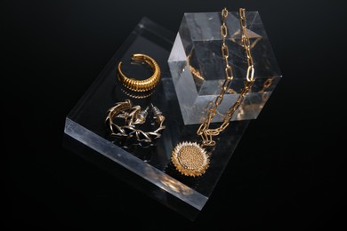Photo of Stylish presentation of gold jewelry on black background