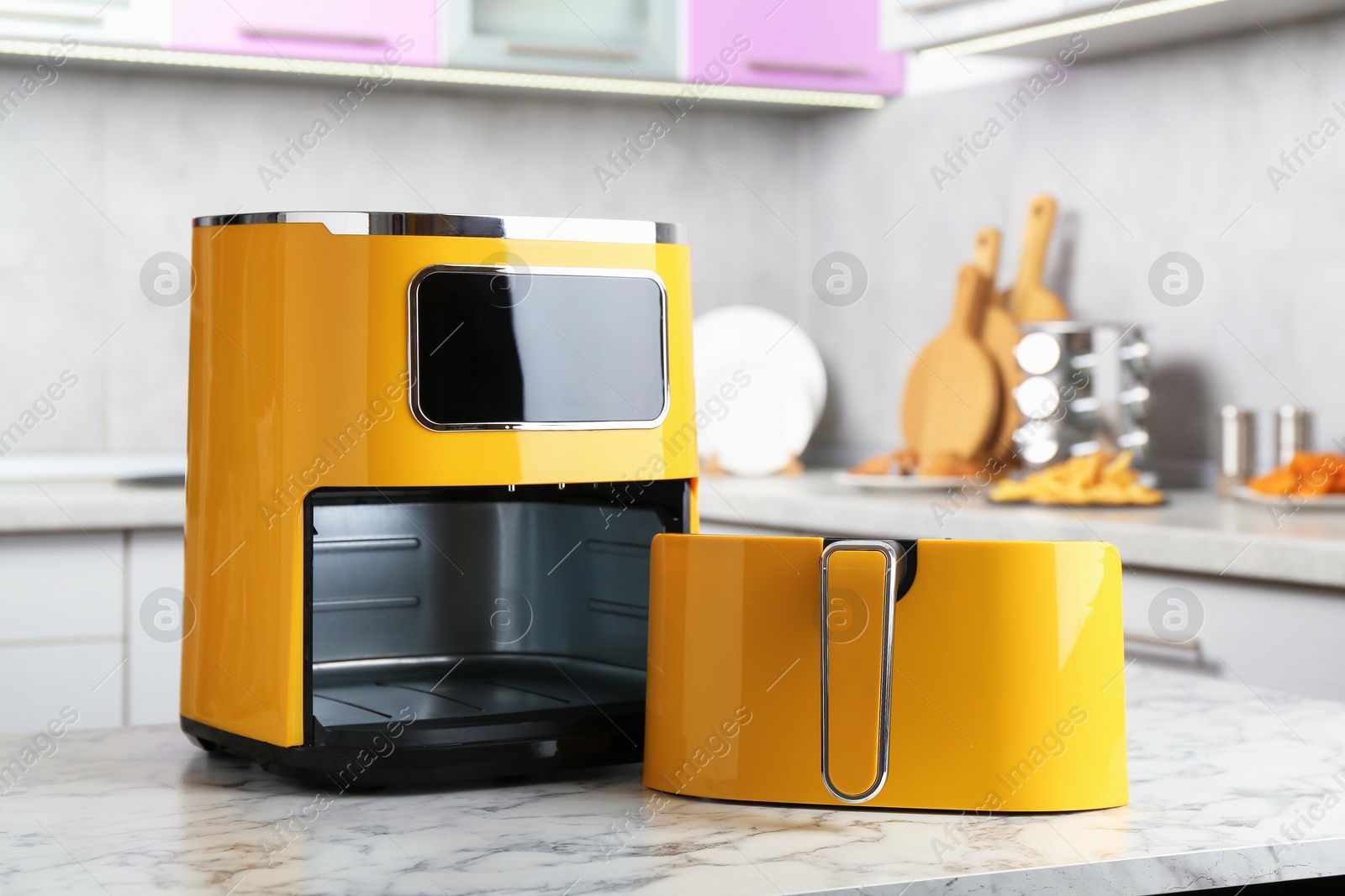 Photo of Modern yellow air fryer on white marble table in kitchen