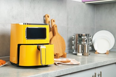 Photo of Modern yellow air fryer on counter in kitchen