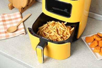 Photo of Air fryer with cooked fries and chicken nuggets on counter