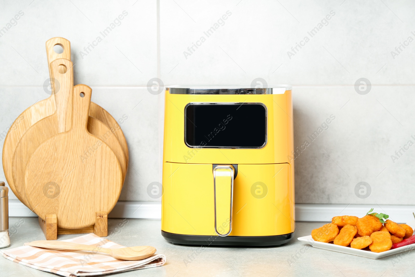 Photo of Air fryer and cooked chicken nuggets on counter in kitchen