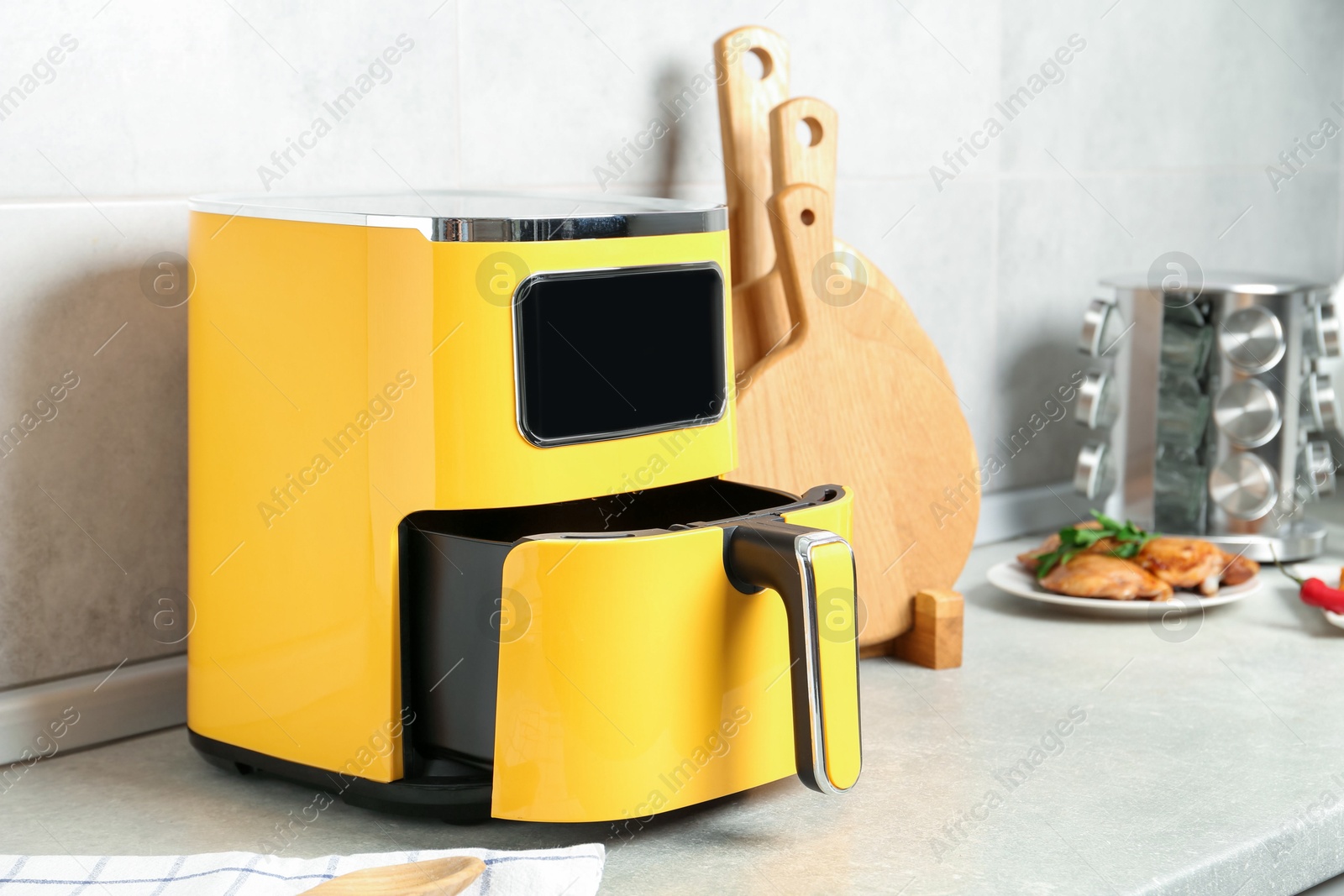 Photo of Modern yellow air fryer on counter in kitchen