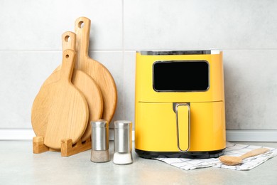 Photo of Modern yellow air fryer and utensils on counter in kitchen
