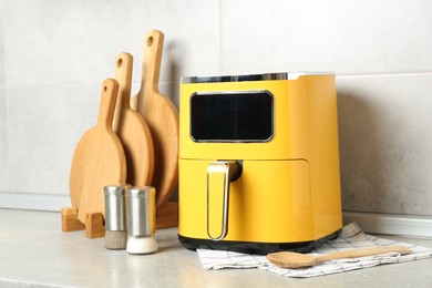 Photo of Modern yellow air fryer and utensils on counter in kitchen