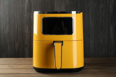 Photo of Modern yellow air fryer on wooden table