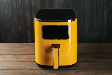 Photo of Modern yellow air fryer on wooden table