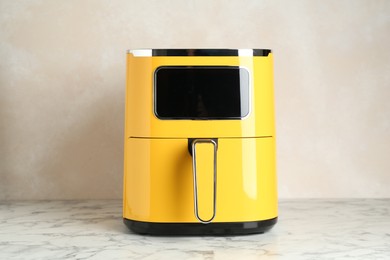 Photo of Modern yellow air fryer on white marble table