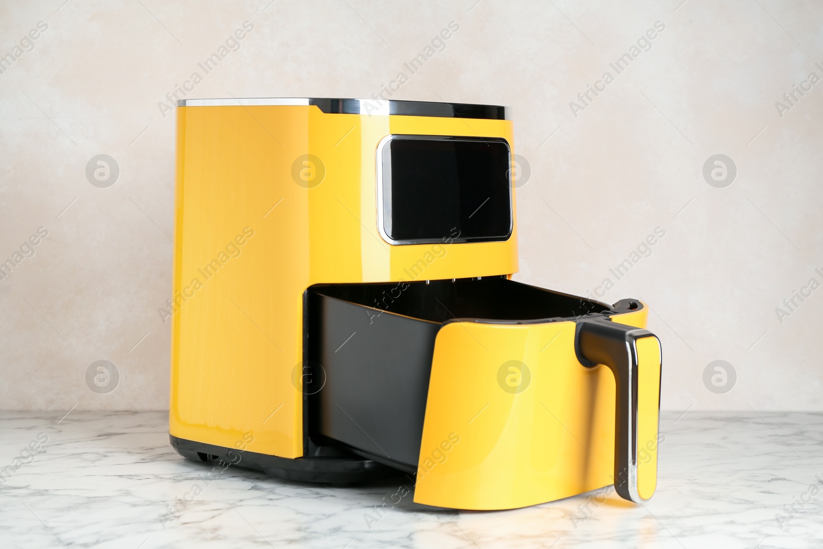 Photo of Modern yellow air fryer on white marble table