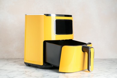 Photo of Modern yellow air fryer on white marble table