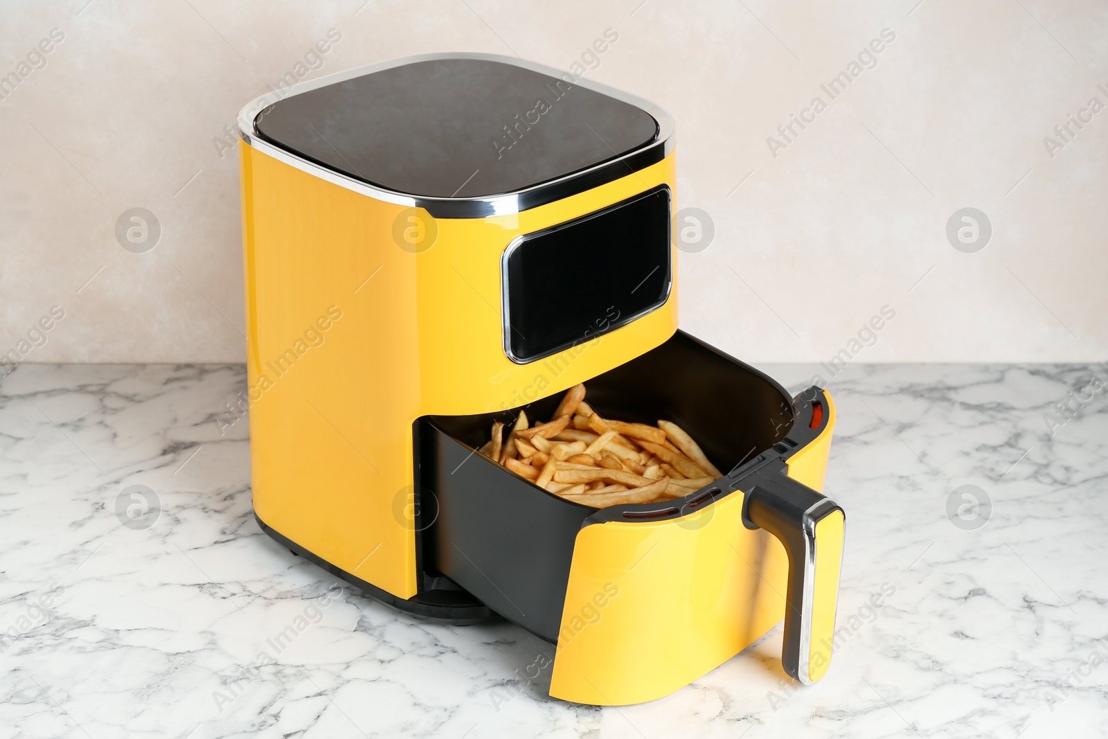 Photo of Air fryer with cooked fries on white marble table