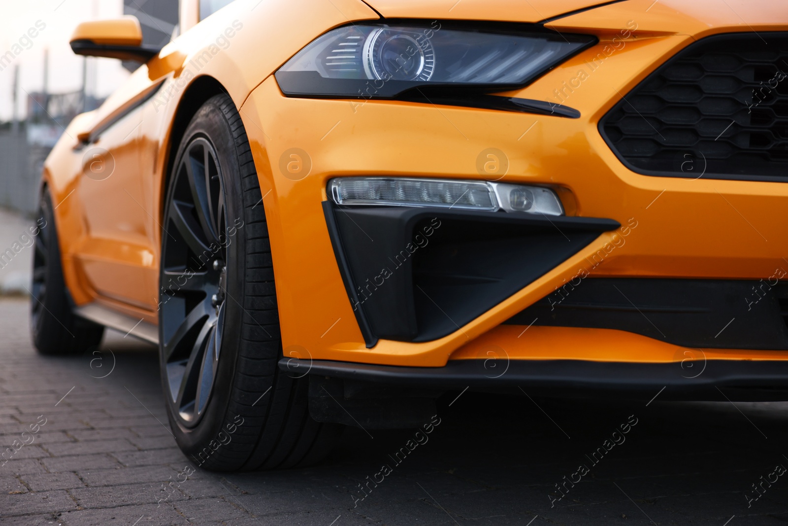 Photo of Modern cabriolet parked on stone pavement outdoors, closeup