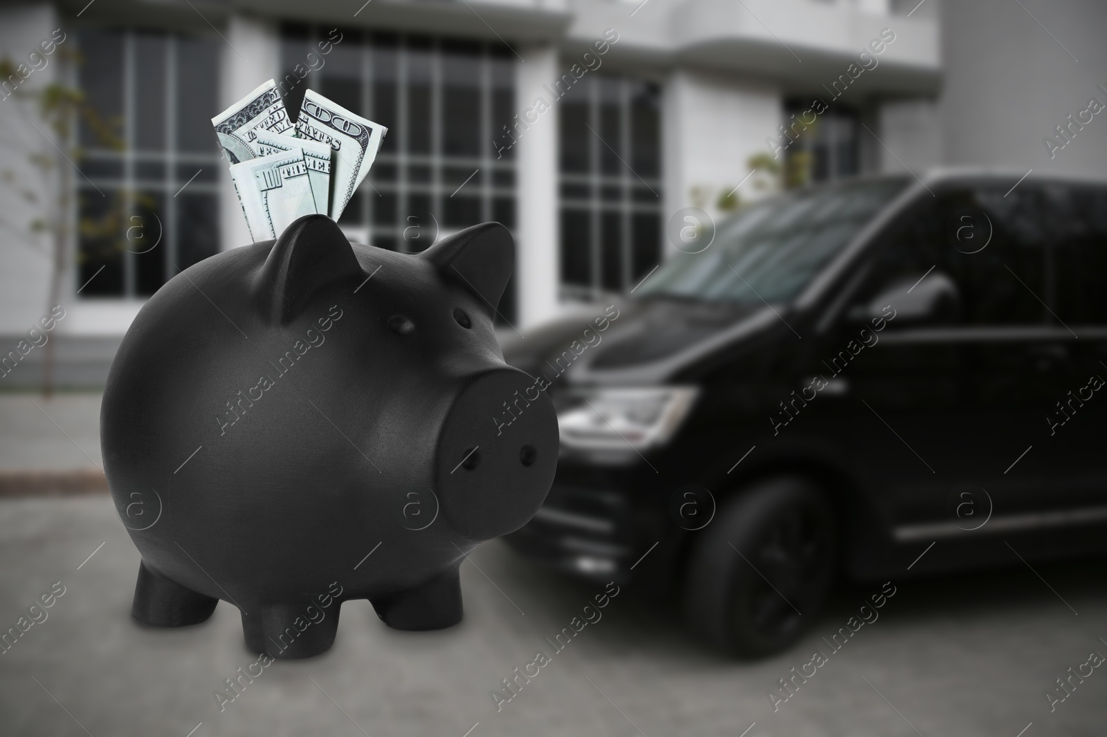 Image of Save money for car. Black piggy bank with dollars against blurred automobile