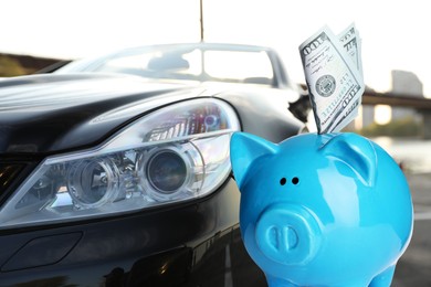 Image of Save money for car. Blue piggy bank with dollars against automobile