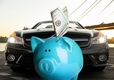 Image of Save money for car. Blue piggy bank with dollars against automobile