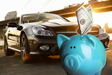 Image of Save money for car. Blue piggy bank with dollars against automobile