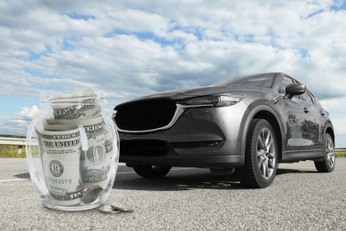 Image of Save money for car. Glass jar with cash near auto outdoors