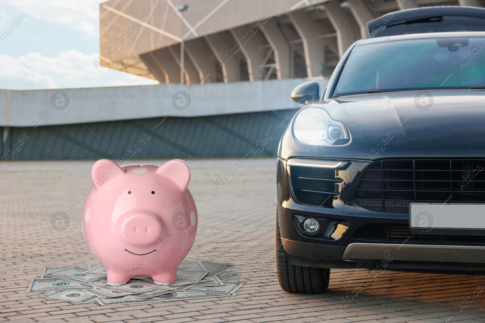 Image of Save money for car. Pink piggy bank and dollars near automobile outdoors