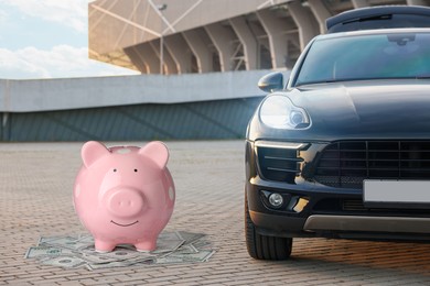 Image of Save money for car. Pink piggy bank and dollars near automobile outdoors