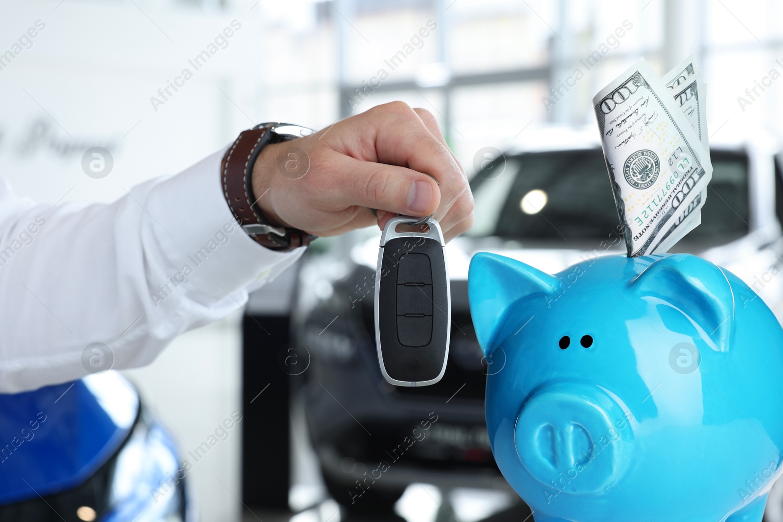 Image of Save money for car. Piggy bank with dollars and man holding car key indoors
