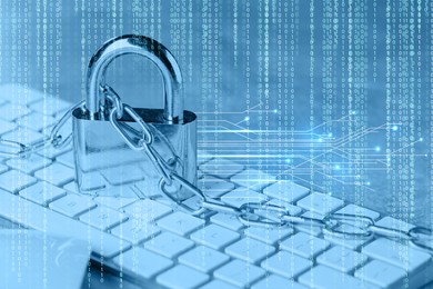 Image of Padlock and chain on computer keyboard, toned in blue. Circuit board pattern and binary code. Cyber security