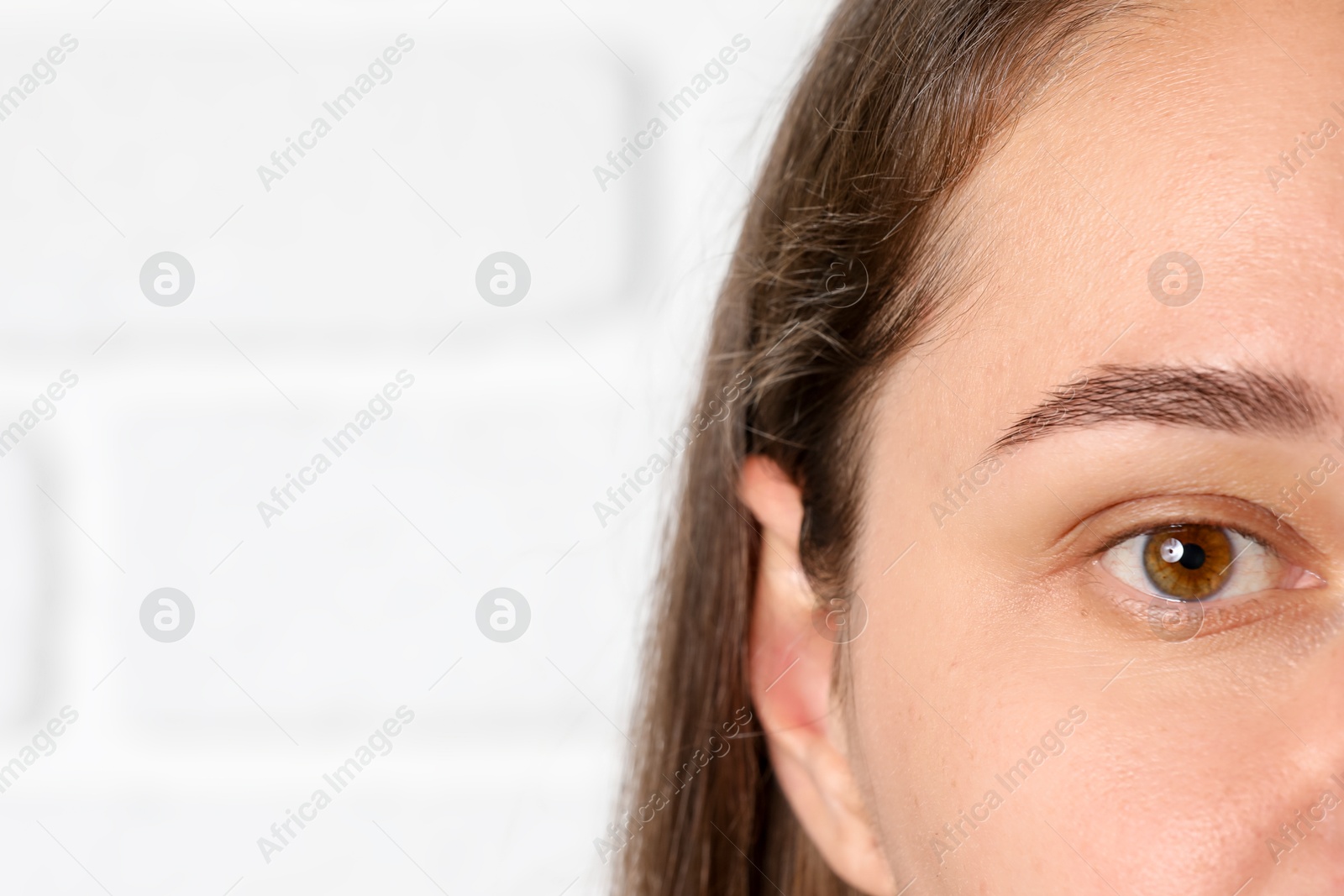Photo of Woman with beautiful eyes on blurred light background, closeup. Space for text