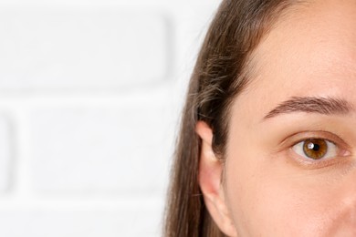 Photo of Woman with beautiful eyes on blurred light background, closeup. Space for text