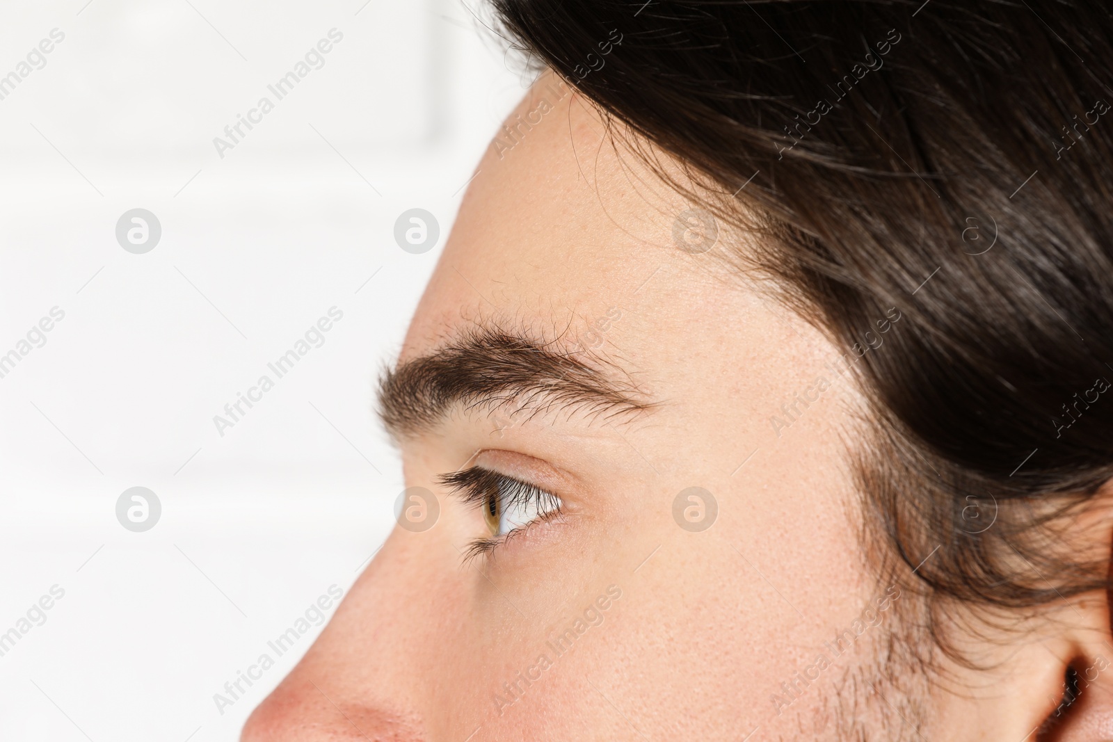 Photo of Man with beautiful eyes on blurred light background, closeup