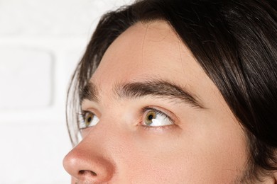 Photo of Man with beautiful eyes on blurred light background, closeup