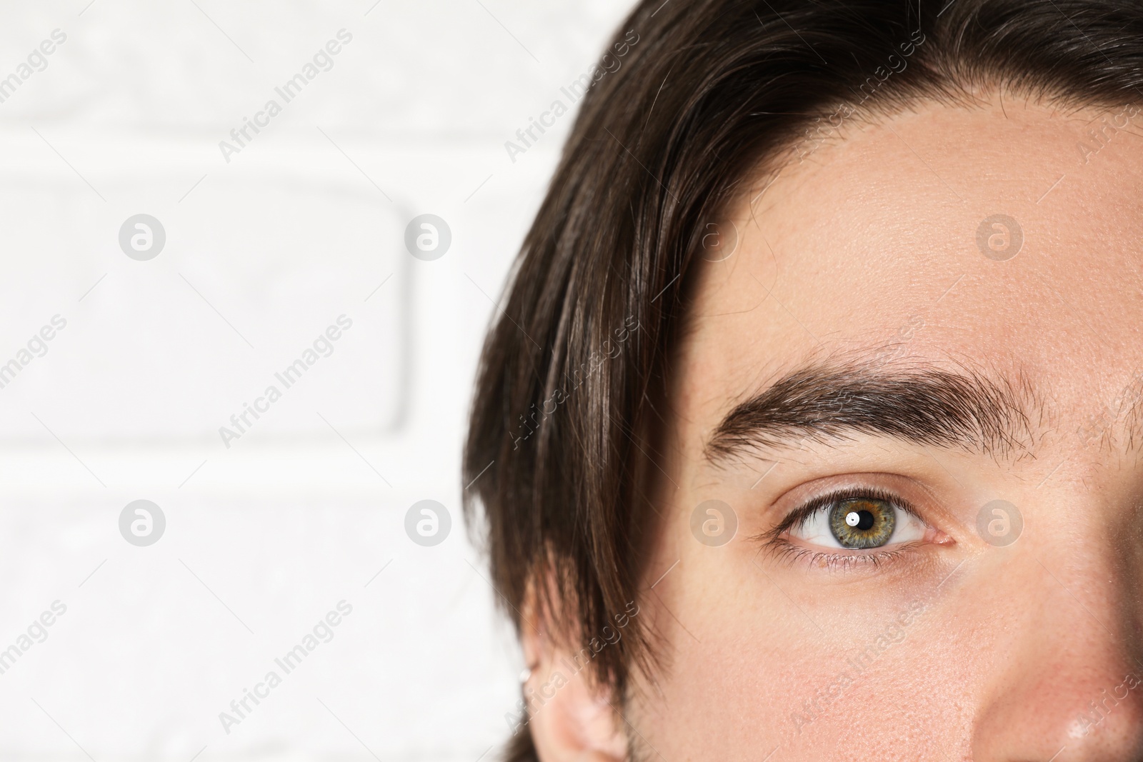 Photo of Man with beautiful eyes on blurred light background, closeup. Space for text