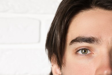 Photo of Man with beautiful eyes on blurred light background, closeup. Space for text
