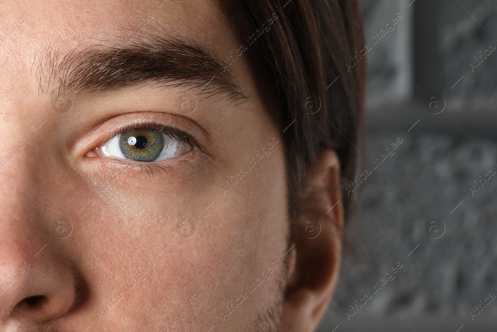 Photo of Man with beautiful eyes near light grey textured wall, closeup
