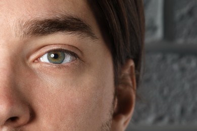 Photo of Man with beautiful eyes near light grey textured wall, closeup