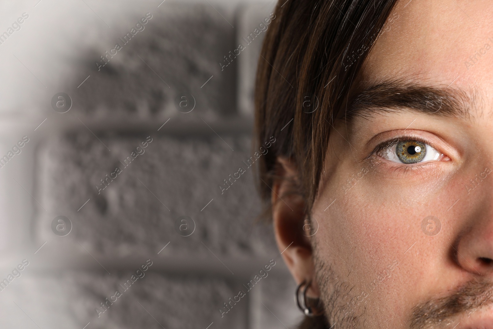 Photo of Man with beautiful eyes near light grey textured wall, closeup. Space for text