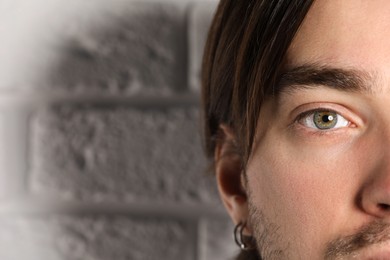 Photo of Man with beautiful eyes near light grey textured wall, closeup. Space for text