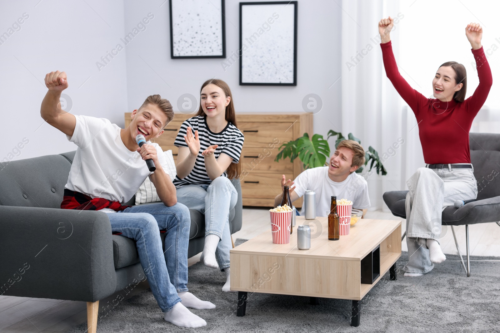 Photo of Young man singing karaoke with friends at home