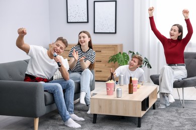 Photo of Young man singing karaoke with friends at home