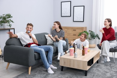 Photo of Young man singing karaoke with friends at home